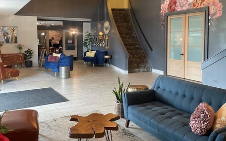 A spacious living area with a chandelier, a blue sofa, and a staircase.