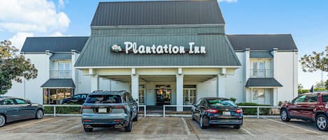The exterior of the Plantation Inn hotel with a parking lot in front.