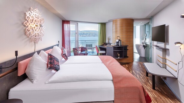 A hotel room with two beds, a desk, a TV, and a balcony with a view.