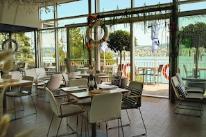 Een restaurant met uitzicht op een meer, met tafels en stoelen voor diners.
