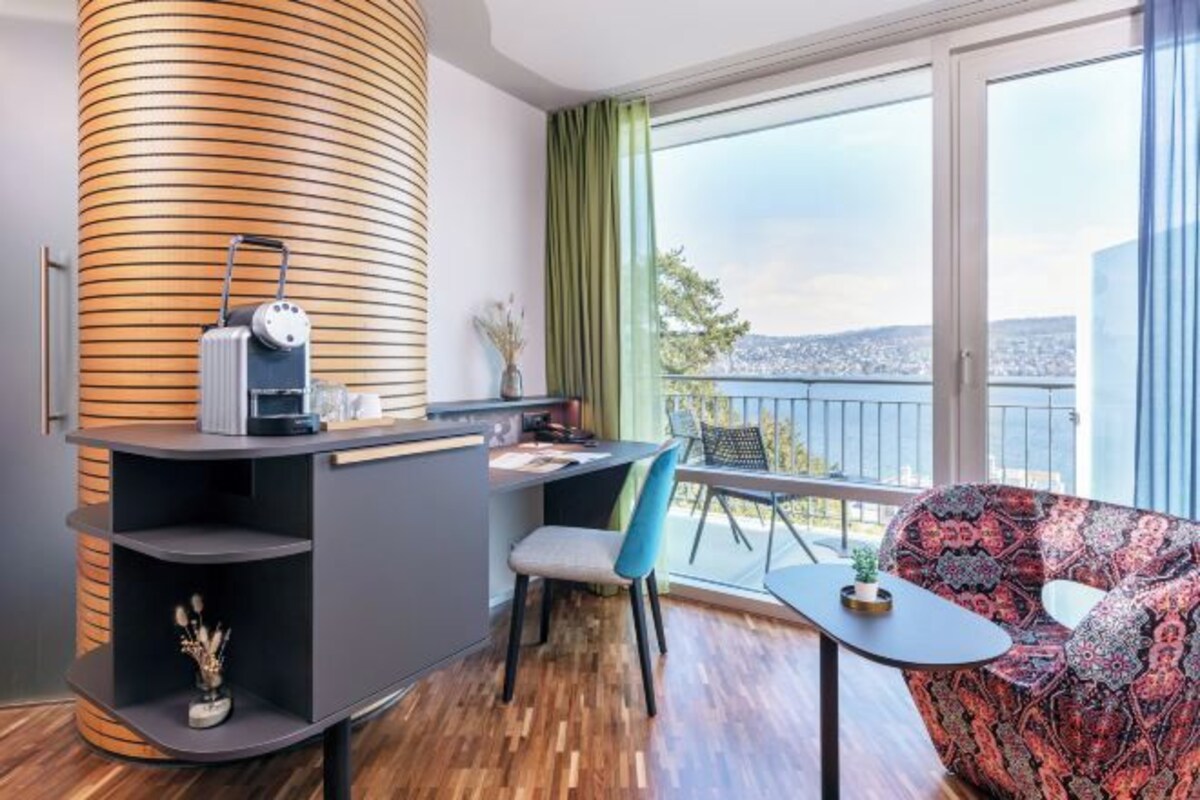 Een moderne woonkamer met een gebogen houten kolom, een bank, een eettafel en een uitzicht op een stadsgezicht door grote ramen.