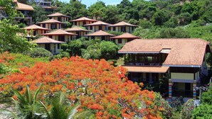 A hillside resort with multiple buildings featuring red-tiled roofs and a lush, green environment. - Hibiscus Beach Pousada (Búzios)