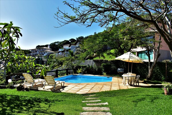 Una piscina al aire libre, sombrillas, sillones reclinables de piscina