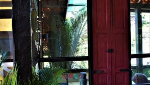 A room with a large window, a red door, and a potted plant. - Hibiscus Beach Pousada (Búzios)