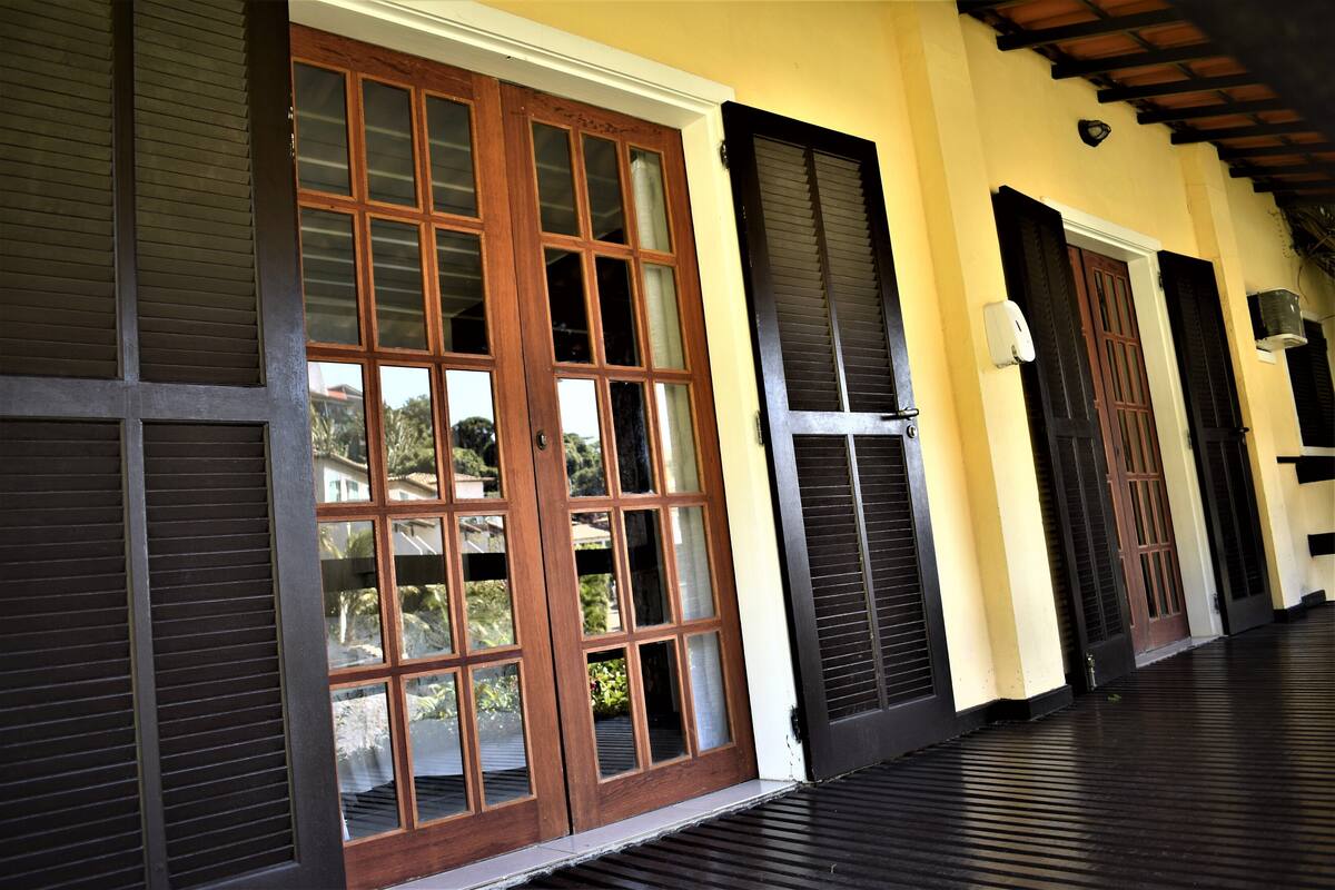 A building with large wooden doors and shutters, a tiled floor, and a yellow wall.