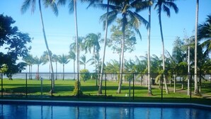 Una piscina con vistas a un área verde y palmeras.