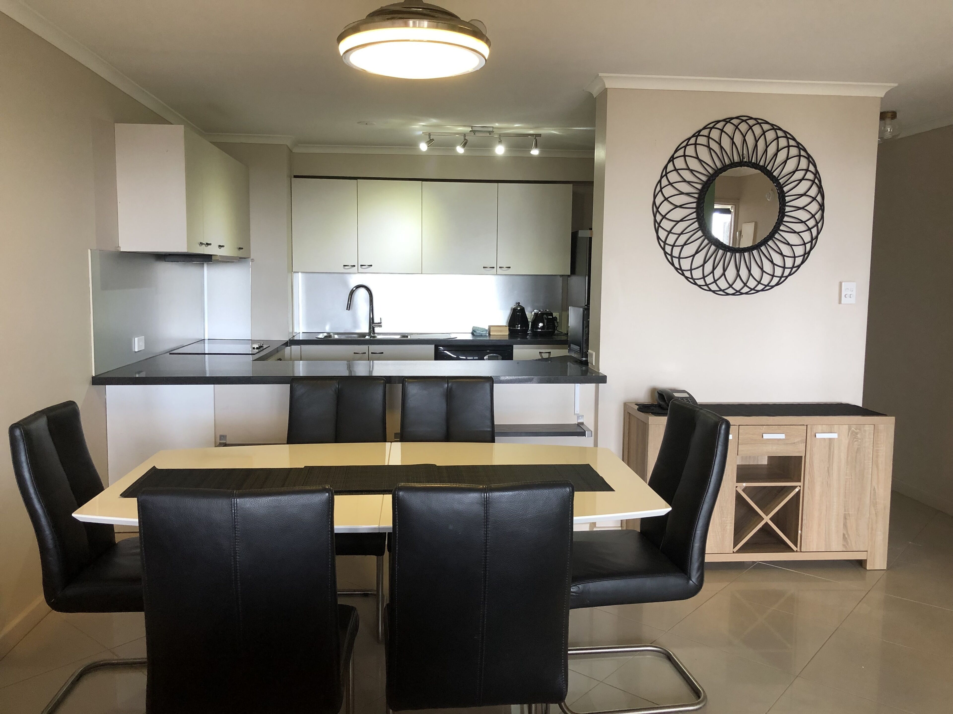 Una cocina moderna con armarios blancos, encimera negra y una isla integrada con asientos.