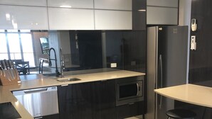 Una cocina moderna con una isla central, electrodomésticos de acero inoxidable y un taburete de bar.