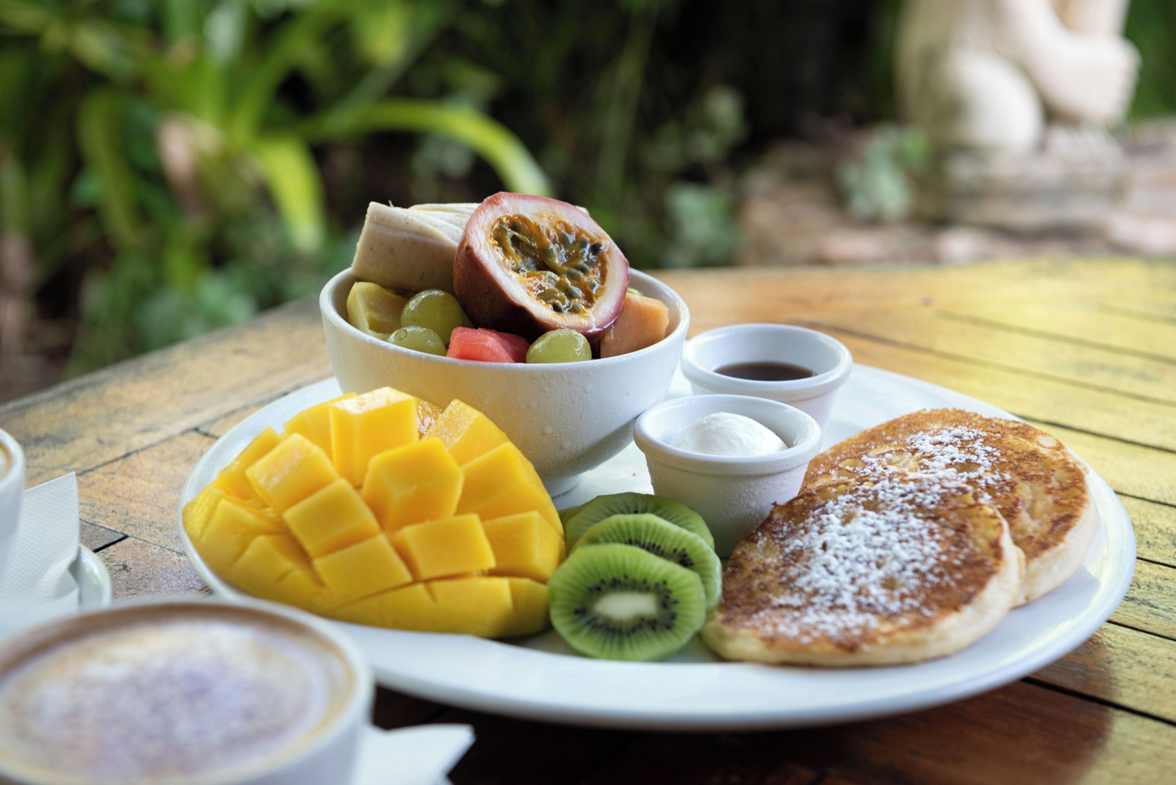 A plate of food including pancakes, fruit, and condiments.