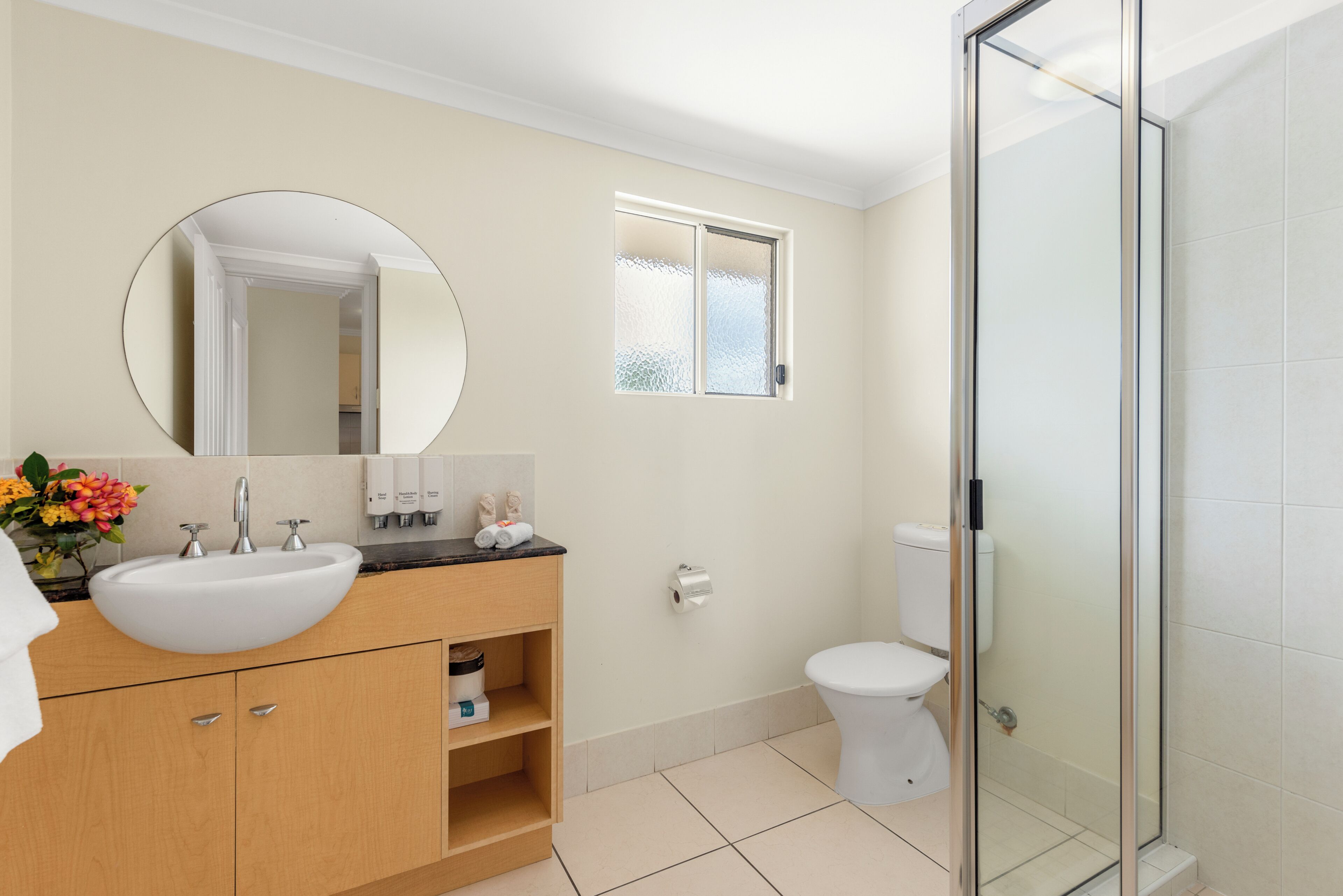 A bathroom with a sink, mirror, toilet, and glass shower enclosure.