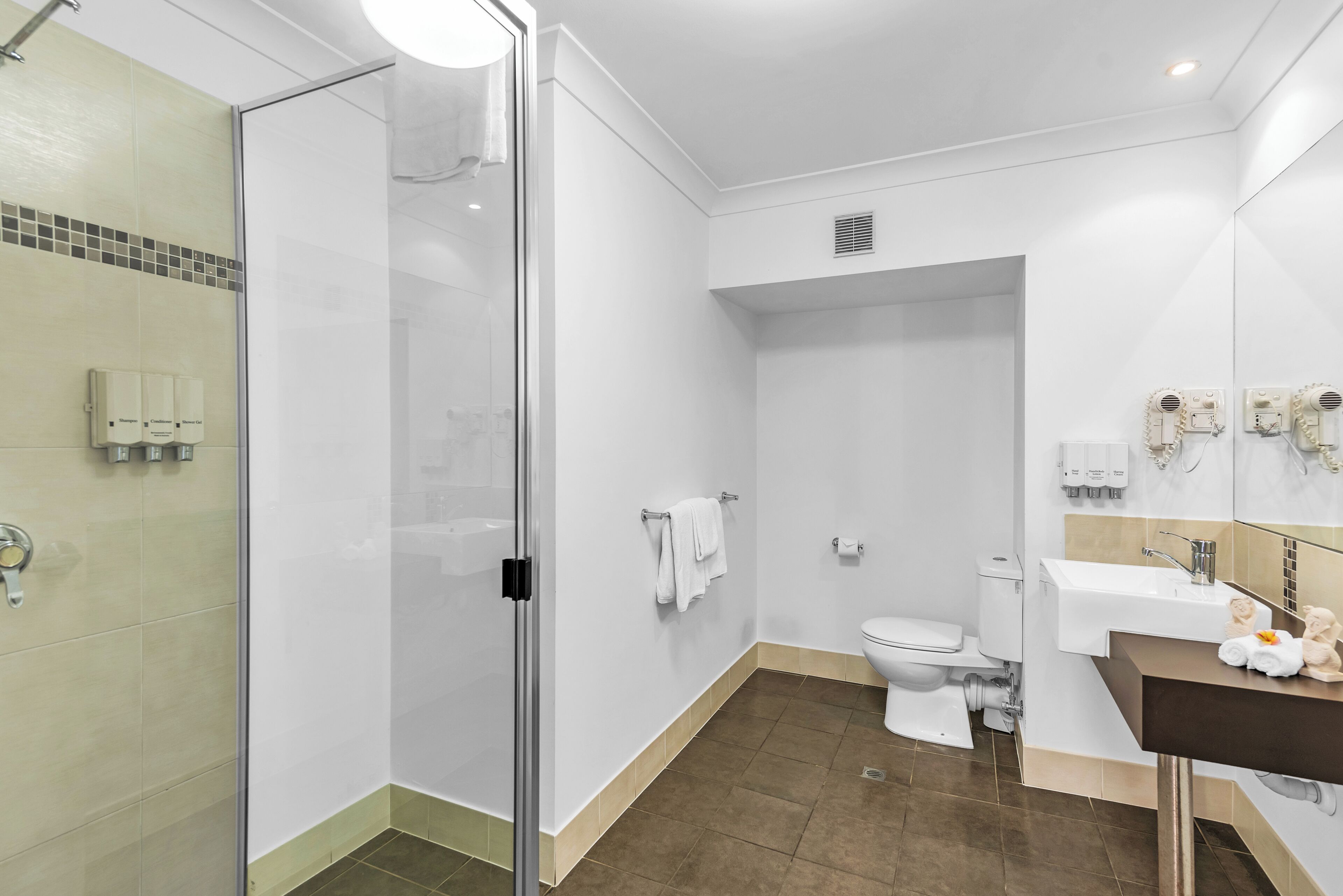Ein modernes Badezimmer mit Duschkabine aus Glas, Toilette, Waschbecken mit Spiegel und Handtuchhalter.