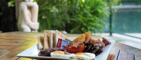 Un plato de desayuno con tostadas, huevos, salchichas y tomates sobre una mesa de madera.