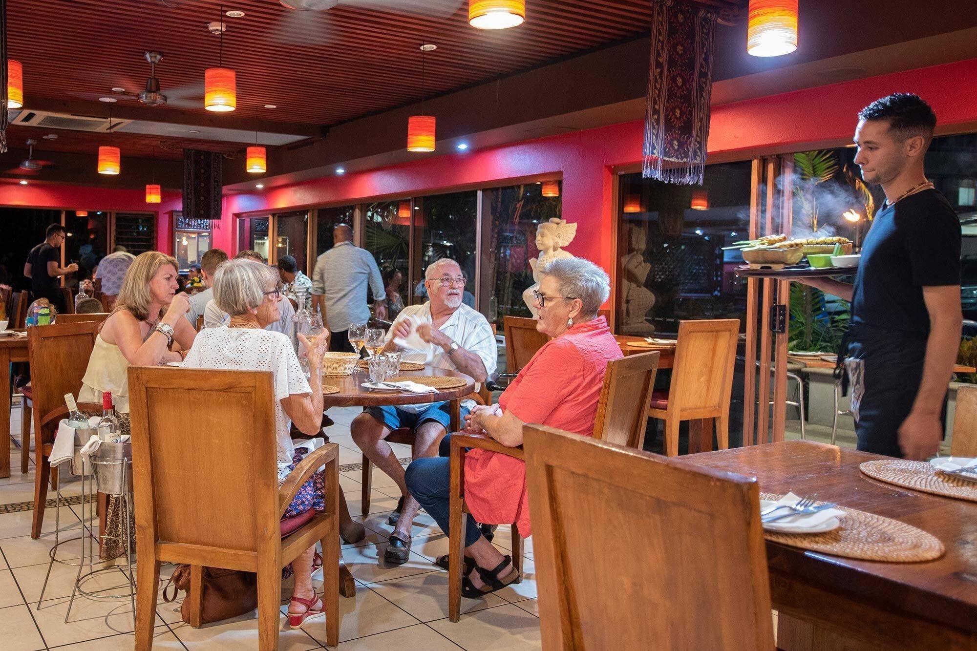Un restaurant avec des meubles en bois, de grandes fenêtres et des lampes suspendues.