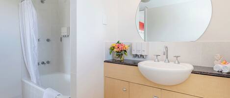 Un baño moderno con una bañera, un espejo grande, un lavabo y un mueble de tocador con armarios.