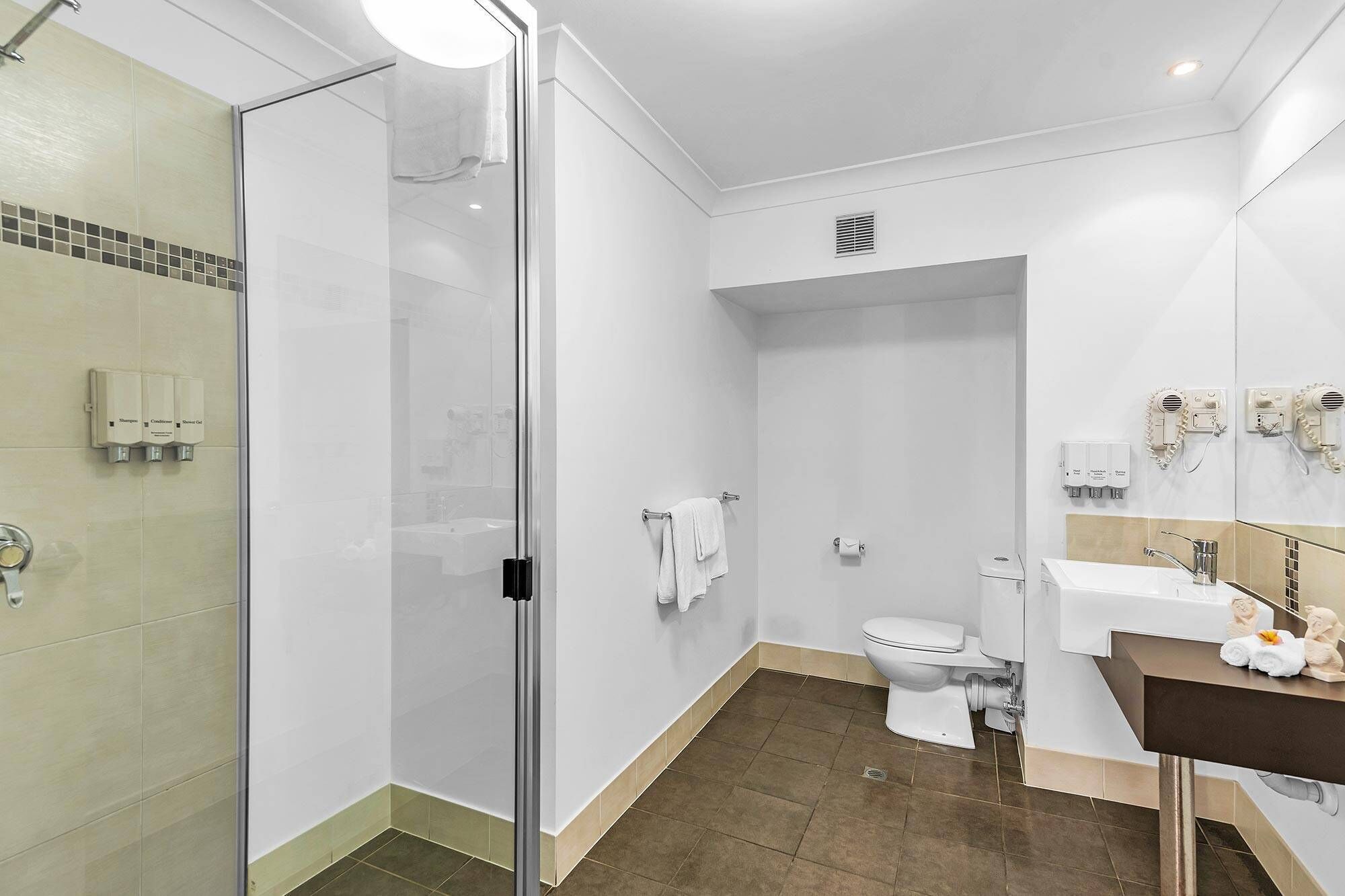 A modern bathroom with a glass shower enclosure, a toilet, a sink with a mirror, and a towel rack.