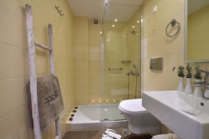 A bathroom with a glass-enclosed shower, a white bathtub, and a white sink.