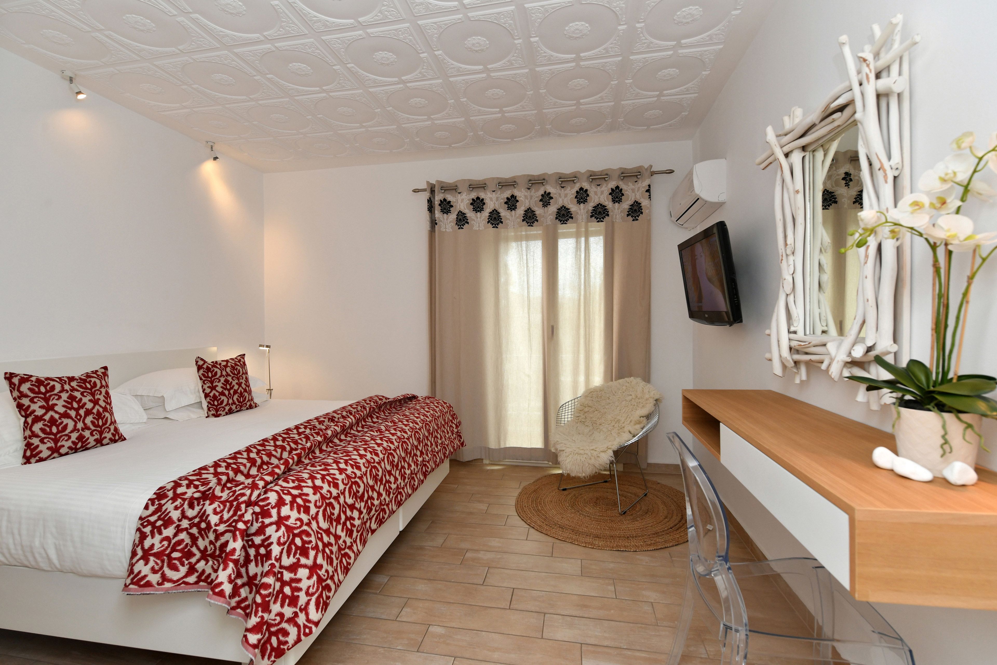 Une chambre à coucher avec un lit, une chaise, un téléviseur et une plante.