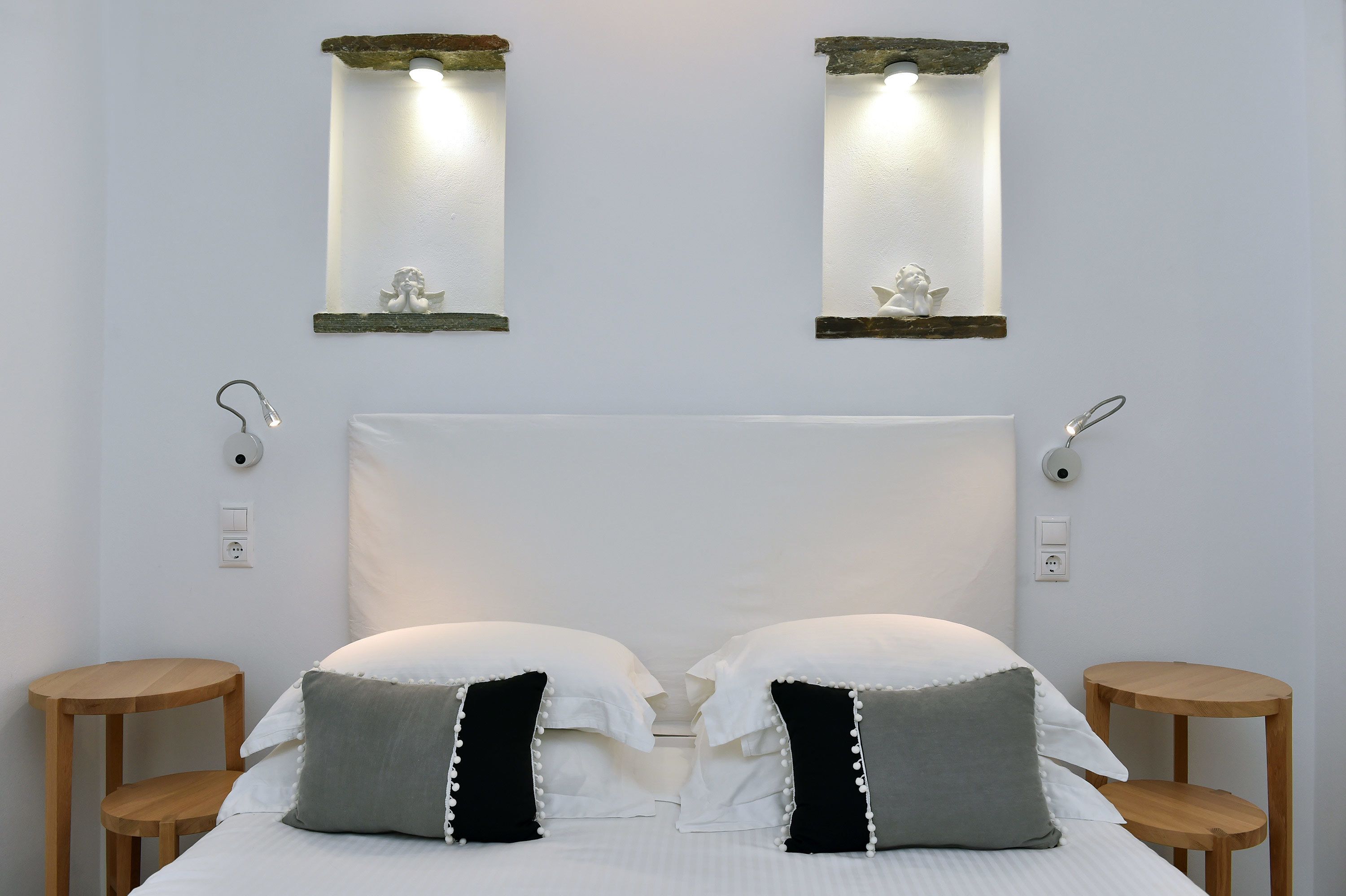 A hotel room with a large bed, two bedside tables, and wall-mounted light fixtures.