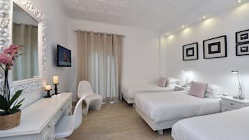 Una habitación de hotel con dos camas, un tocador con espejo, una silla y un televisor.