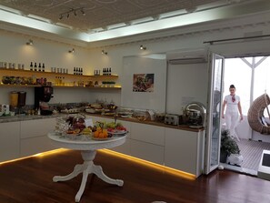 A spacious kitchen with a central island, a variety of food items, and a wine selection on the shelves. - Apollon Boutique Hotel (Paros)