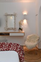 Quarto com cama, cadeira, espelho e mesa de cabeceira com abajur.