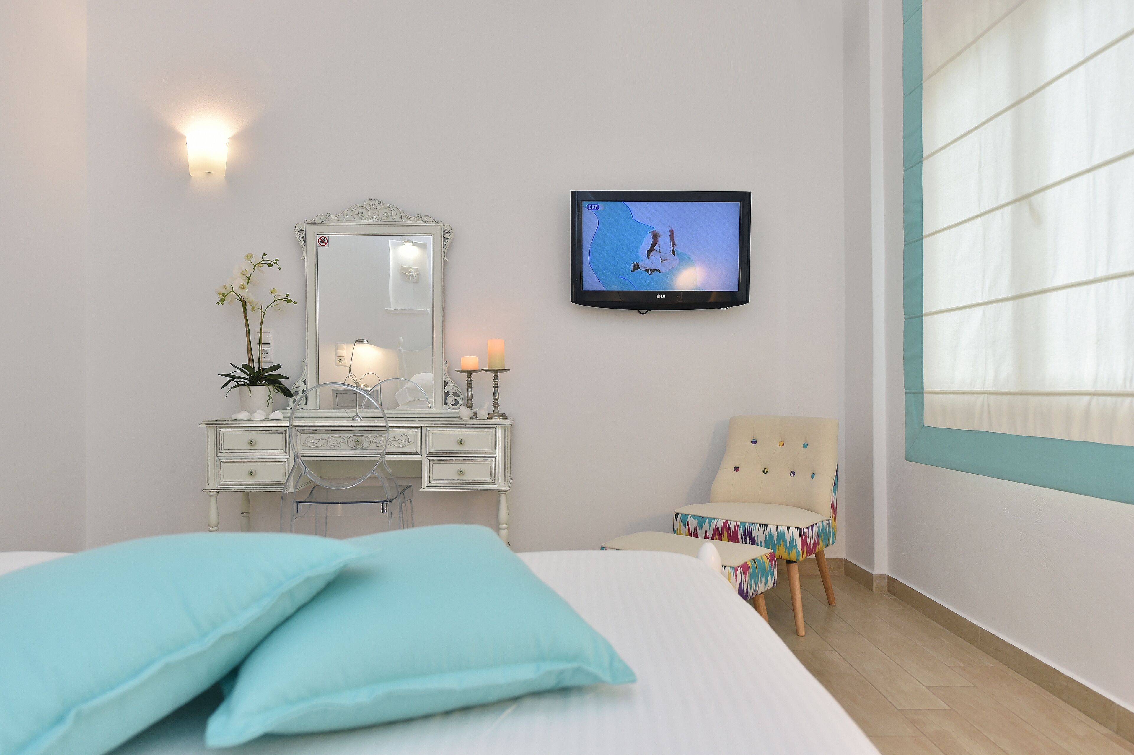 Ein Schlafzimmer mit Bett, Schminktisch, Spiegel, Fernseher und Stuhl.