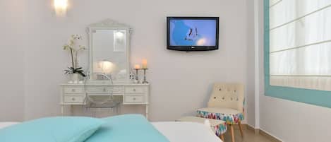 Un dormitorio con cama, cómoda, espejo, televisor y una silla.