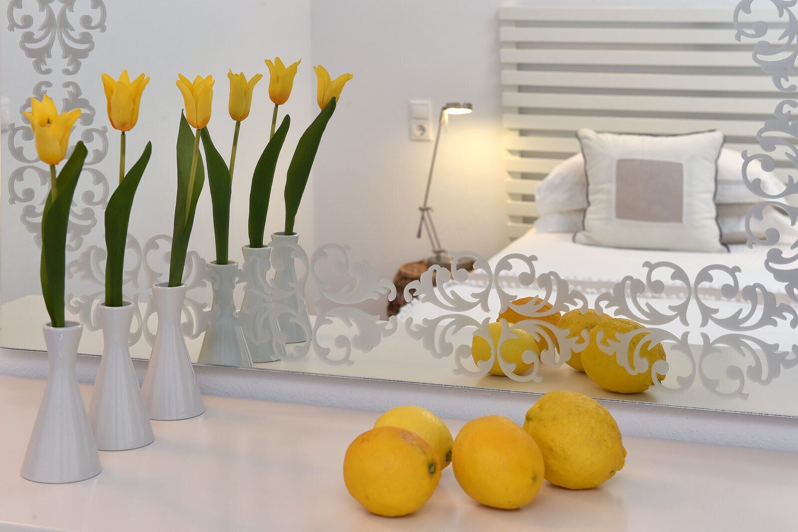 A modern bedroom with a bed, bedside table, and decorative mirror.