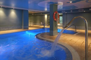 Una piscina techada, una piscina al aire libre, sombrillas