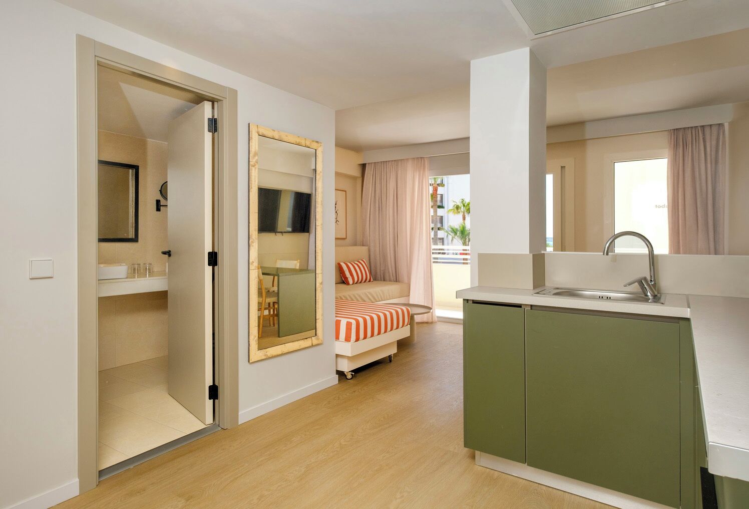 Una habitación de hotel compacta con kitchenette, una cama, un comedor y un baño.