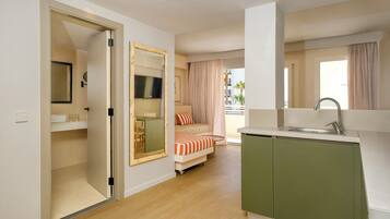 Una habitación de hotel compacta con kitchenette, una cama, un comedor y un baño.
