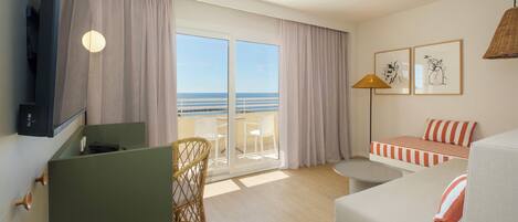 Une chambre d’hôtel avec un balcon, un bureau, un canapé et une lampe.