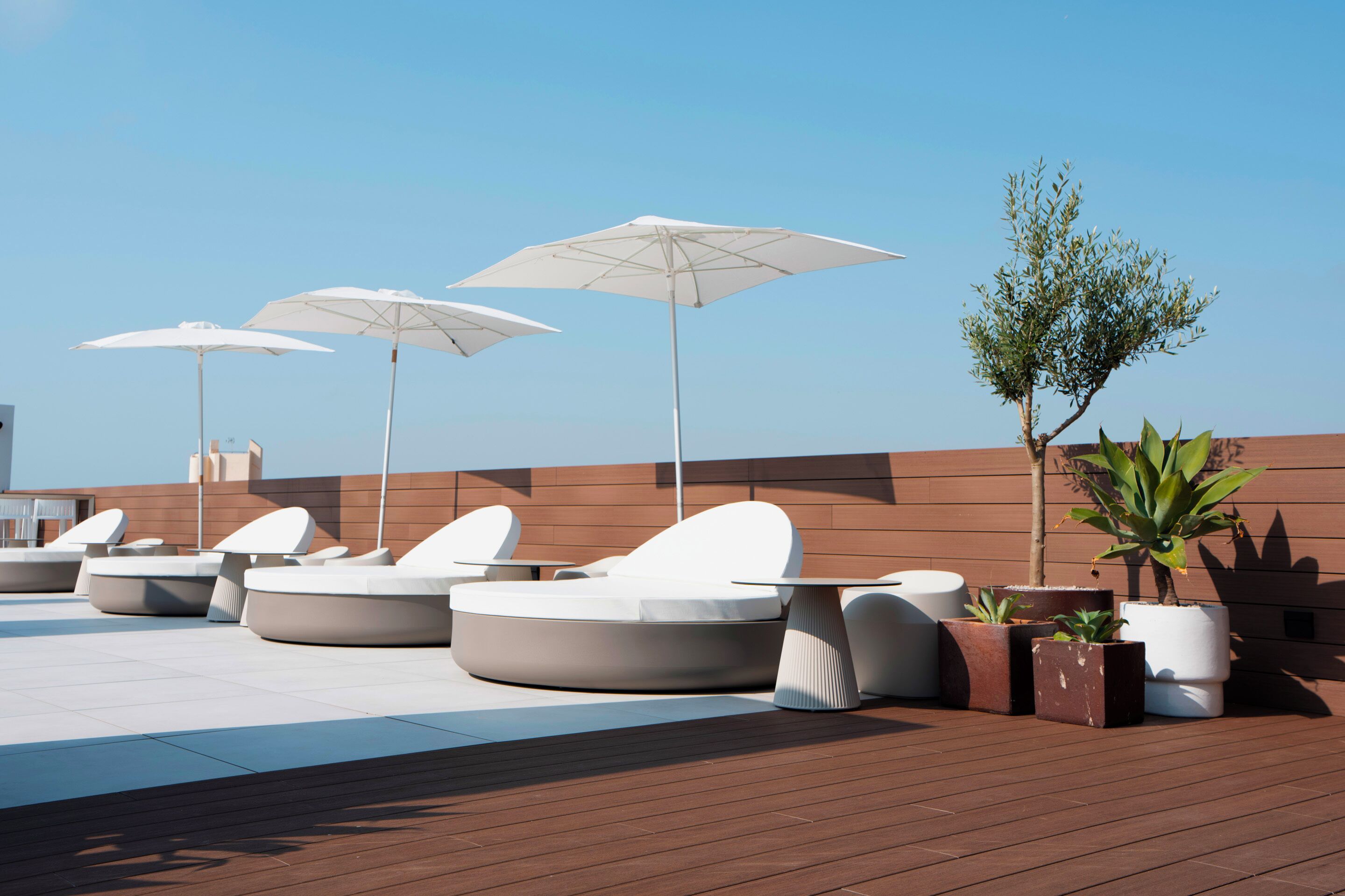 A rooftop lounge area with modern seating and umbrellas.