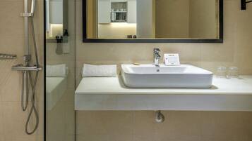 Un baño moderno con cabina de ducha de vidrio, un lavabo blanco con espejo y un perchero de toallas en la pared.