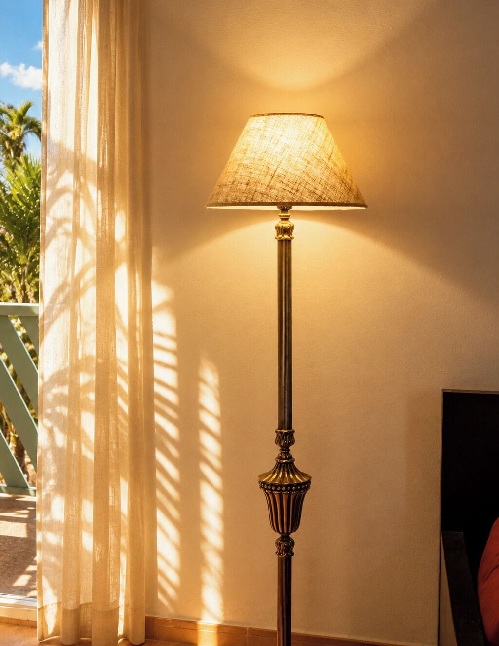 A floor lamp with a textured lampshade, positioned against a wall with a shadow cast by a curtain.