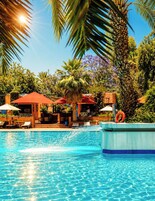 Una piscina al aire libre, sombrillas, sillones reclinables de piscina