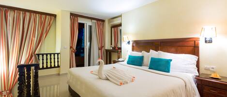 A hotel room with a large bed, a wooden headboard, a nightstand, and a red carpet.