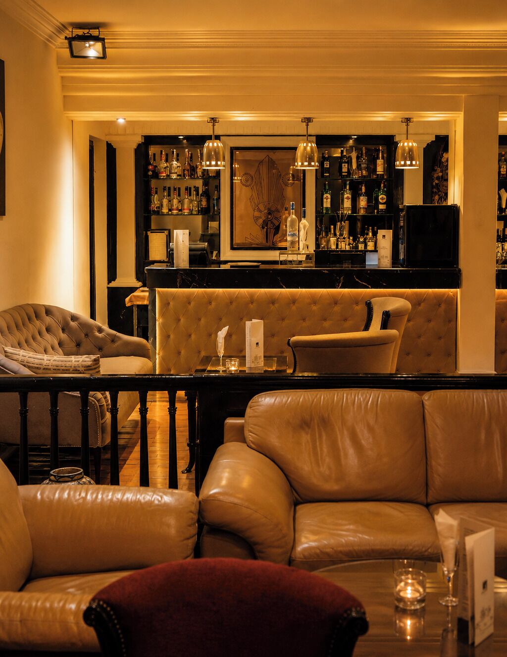 Zona de bar con sofás de cuero, mostrador de bar y lámparas colgantes.