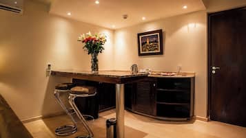 A kitchen with a bar stool, a vase with flowers, a framed picture on the wall, and a door.