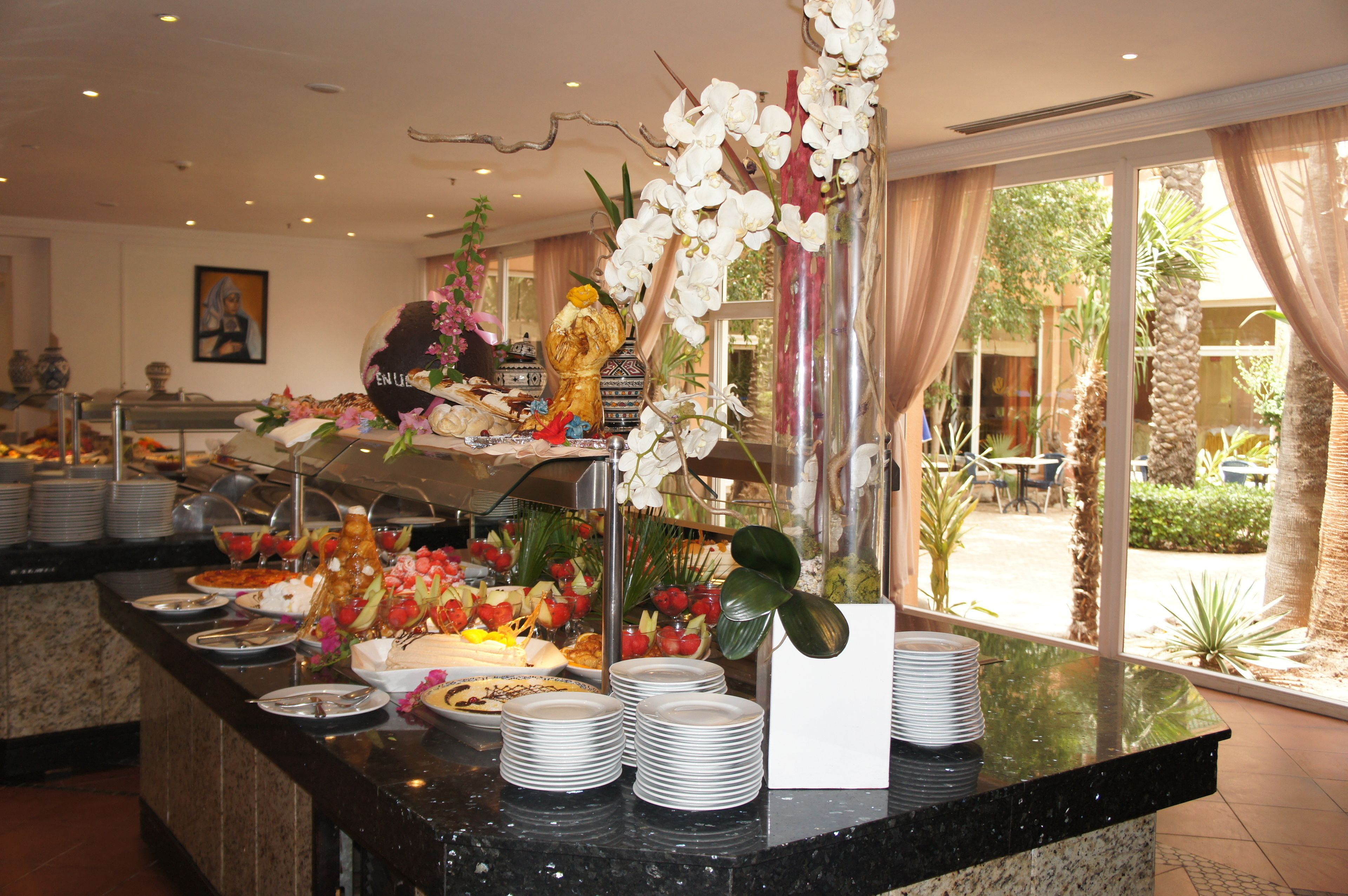 A buffet with various food items and a decorative orchid arrangement.