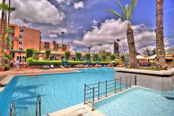 Una piscina al aire libre, sombrillas, tumbonas