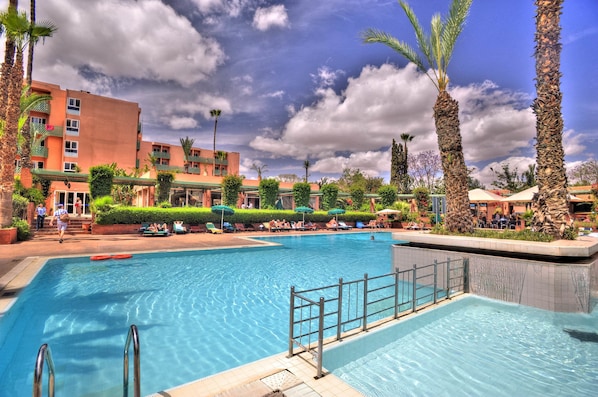 Una piscina al aire libre, sombrillas, tumbonas