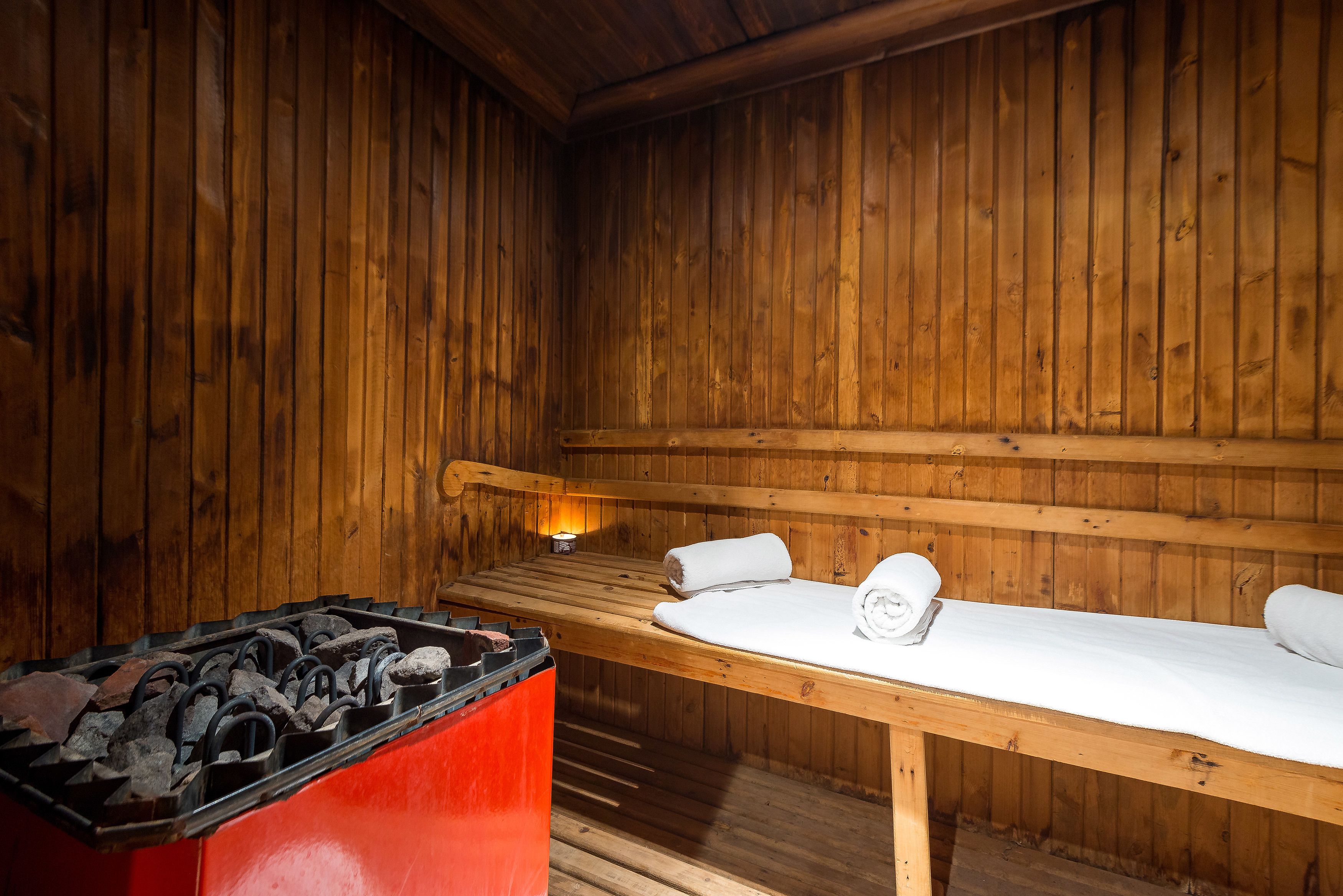 Un sauna con paredes de madera, un banco y un calentador rojo.