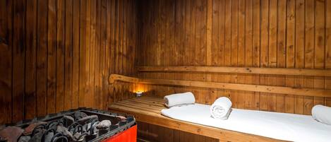Un sauna con paredes de madera, un banco y un calentador rojo.