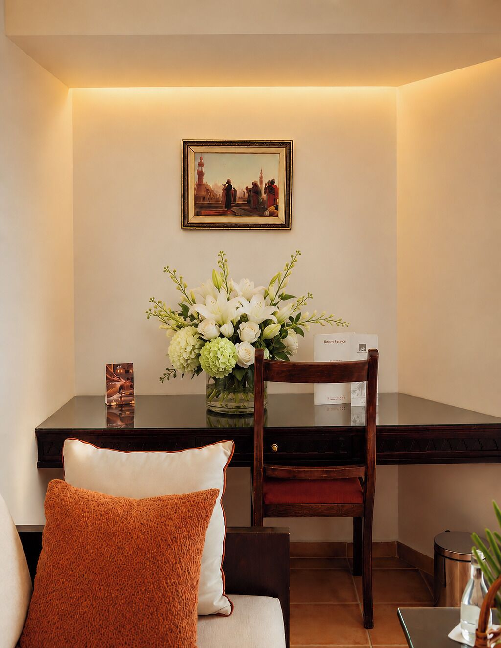 Une chambre d’hôtel avec une table à manger, un vase de fleurs, un tableau encadré au mur et une chaise.
