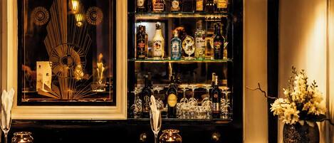A bar area with a marble countertop, two pendant lights, a selection of liquor bottles, glasses, and a decorative mirror.