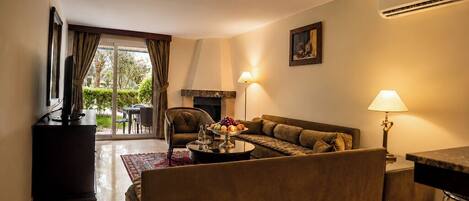 A living room with a sofa, a coffee table with fruit, a fireplace, and a dining area with a table and chairs.