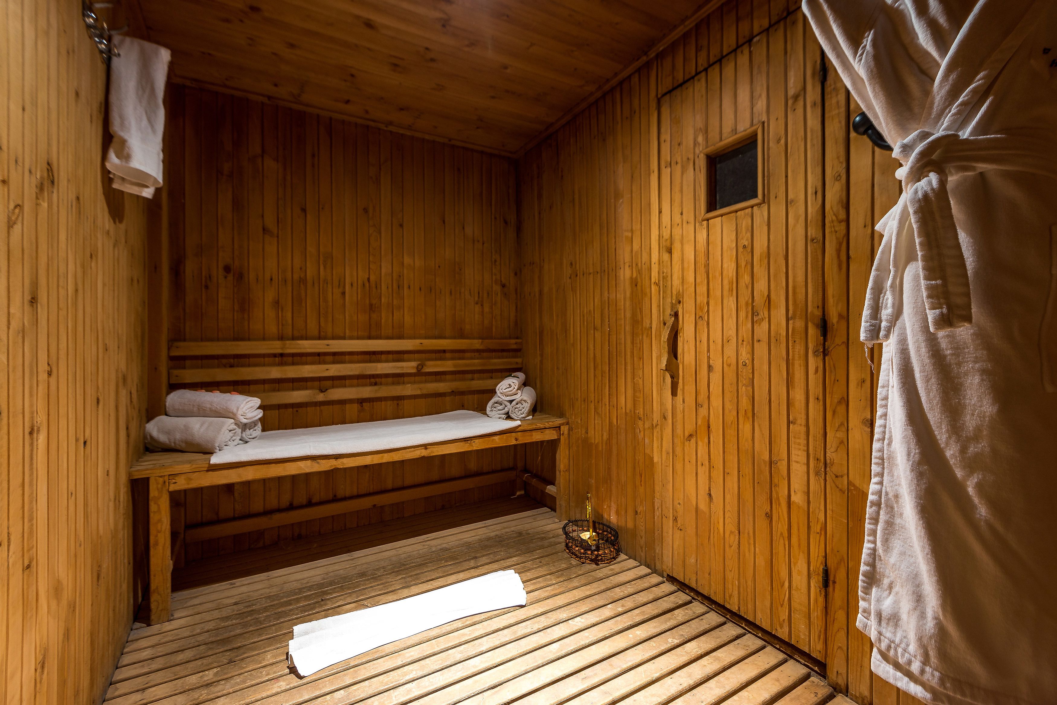 A wooden sauna room with benches, towels, and a small window.