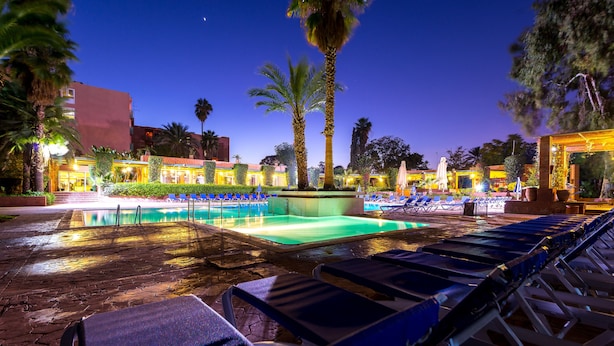 Un espace aménagé au bord de la piscine, avec des chaises longues et une piscine, au crépuscule.