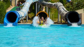 Un toboggan aquatique se terminant par une zone où une personne peut atterrir, le tout entouré d’une piscine.